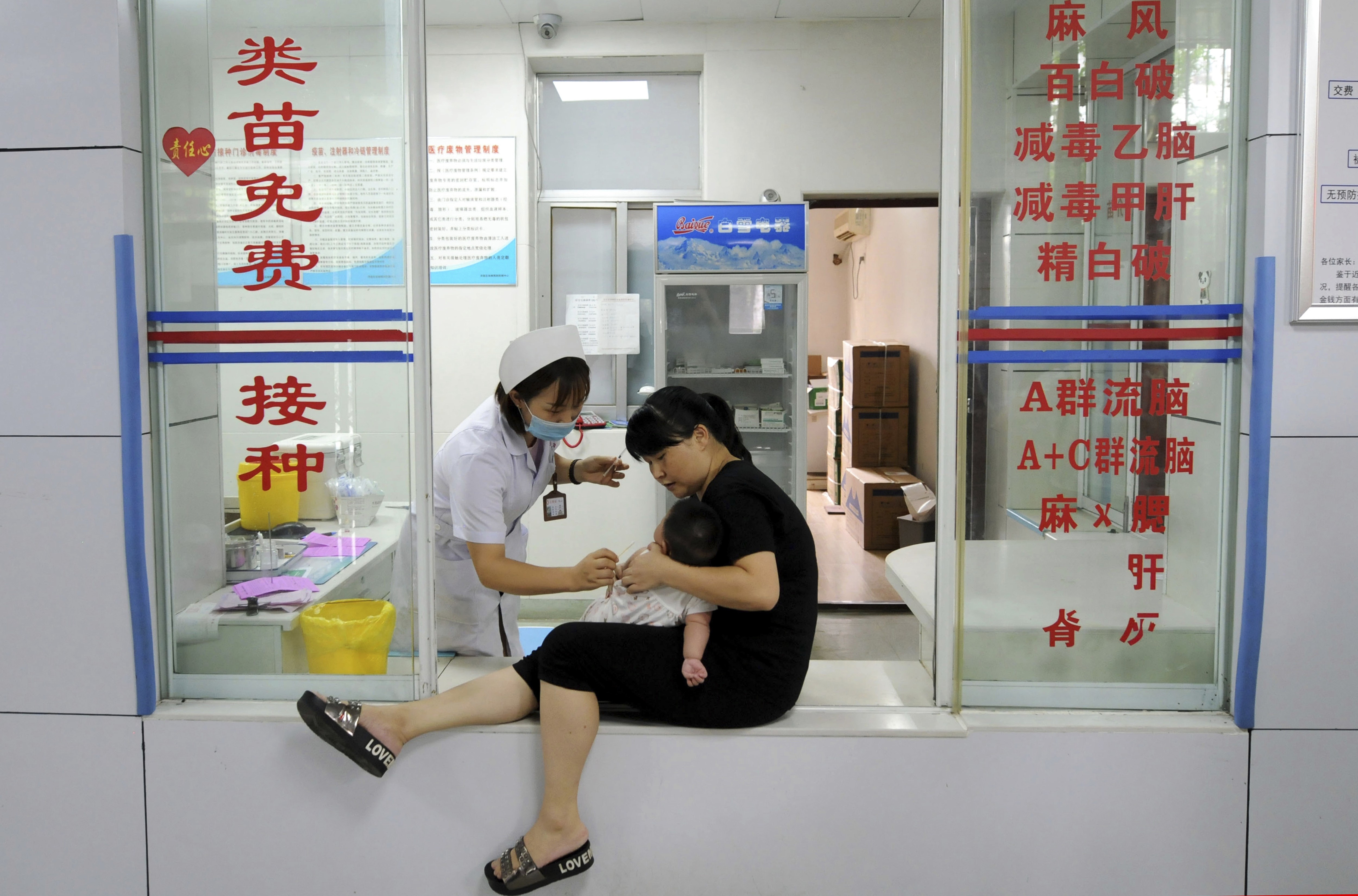 A woman holds an infant as a nurse administers a vaccination in eastern China. Authorities ordered a recall of Changchun Changsheng Life Sciences products after it was found falsifying records. Photo: Chinatopix via AP