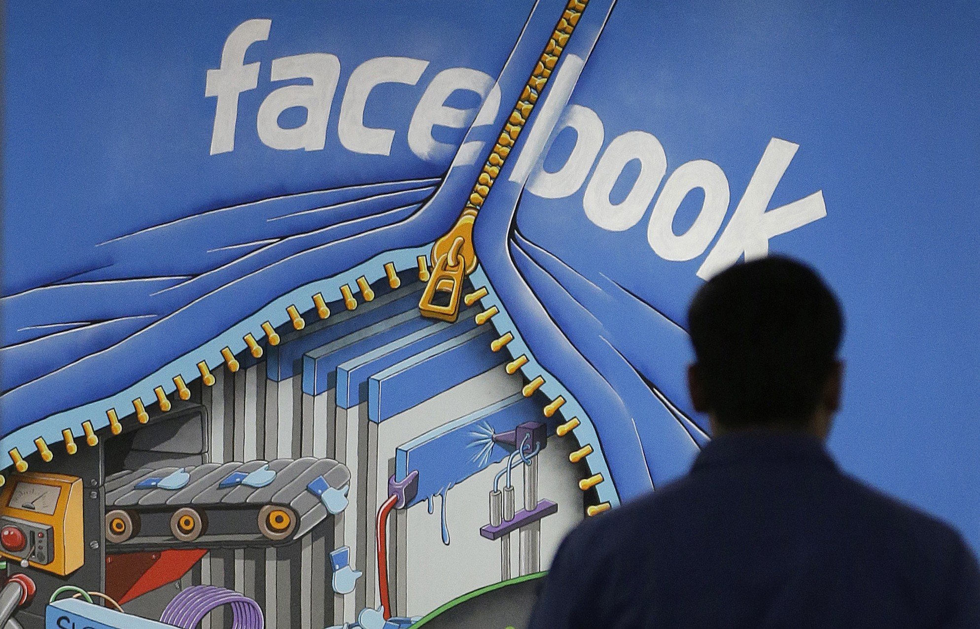 A Facebook employee walks past a sign at the company’s headquarters in Menlo Park, California, in March 2013. Facebook is an example of a company with a business model built around intangible capital. Photo: AP