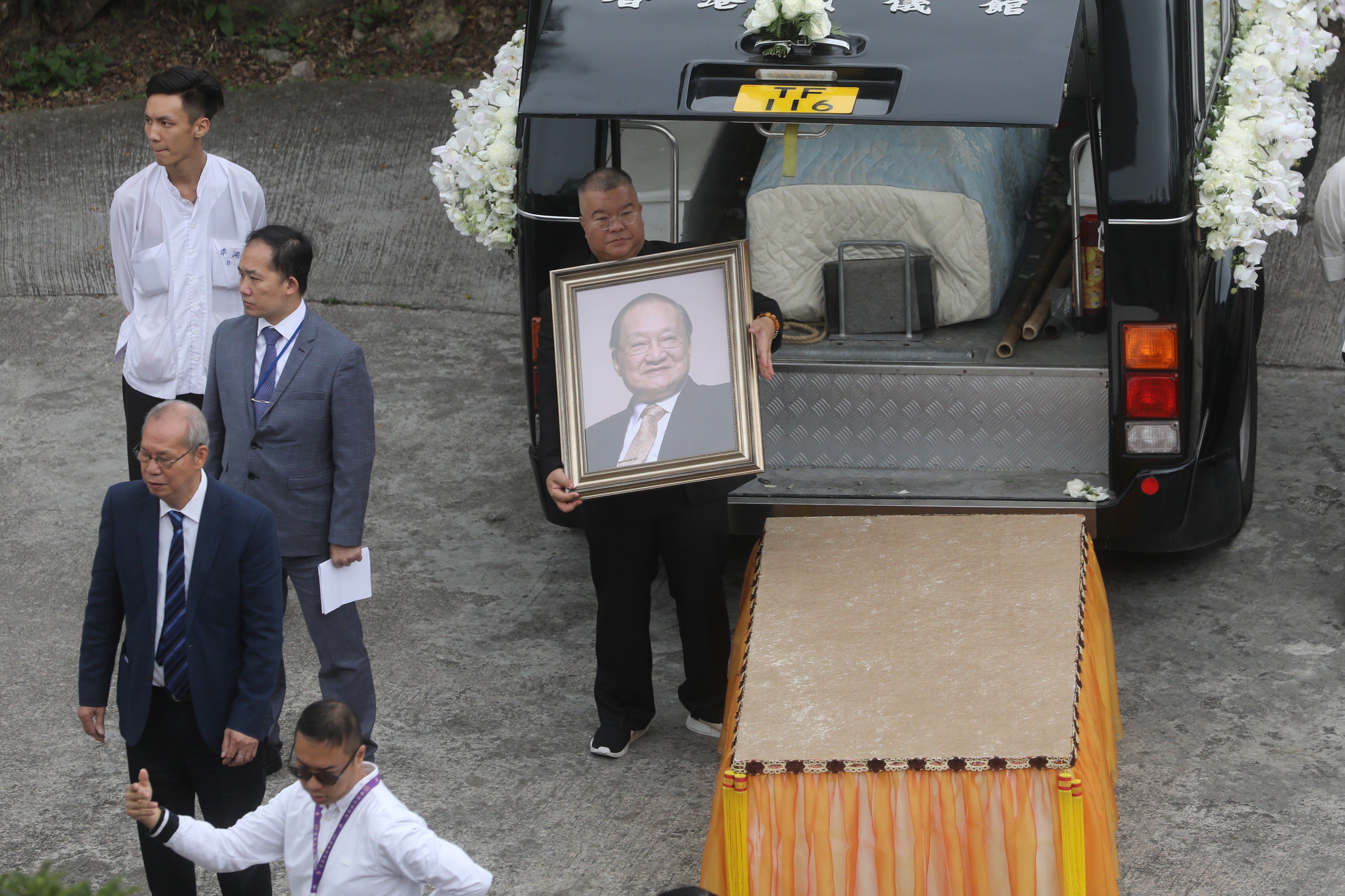 Andrew Cha holds a portrait of his father Louis Cha, as the funeral cortege arrives at Po Lin Monastery, Lantau Island. Photo: Sam Tsang
