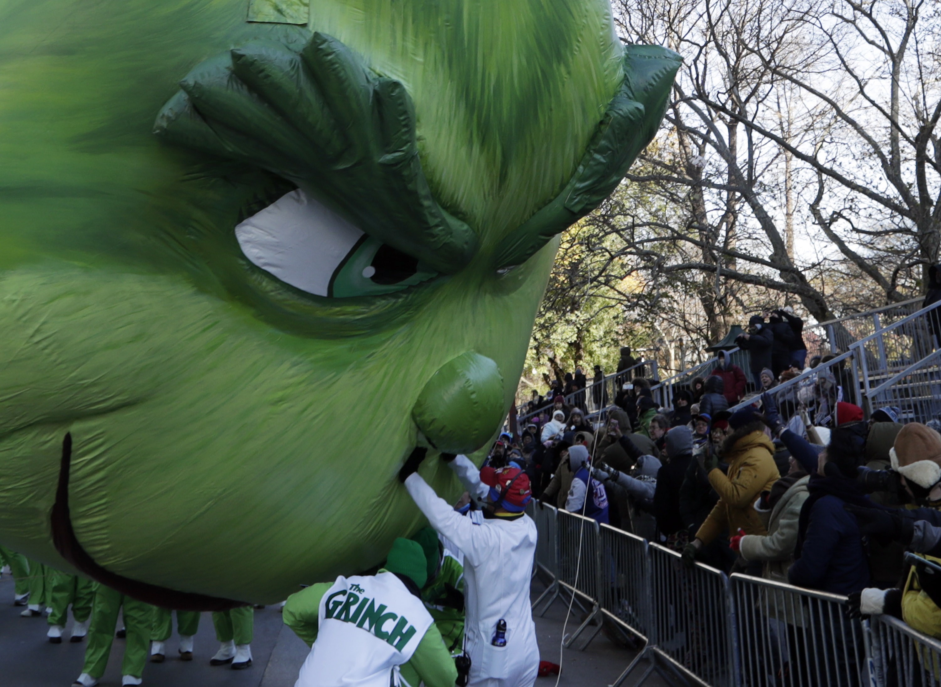 Balloon technicians try and hold back the Grinch balloon from crashing down onto the street and into the crowd as it floats down Central Park West in New York during the Macy's Thanksgiving Day Parade. Photo: EPA