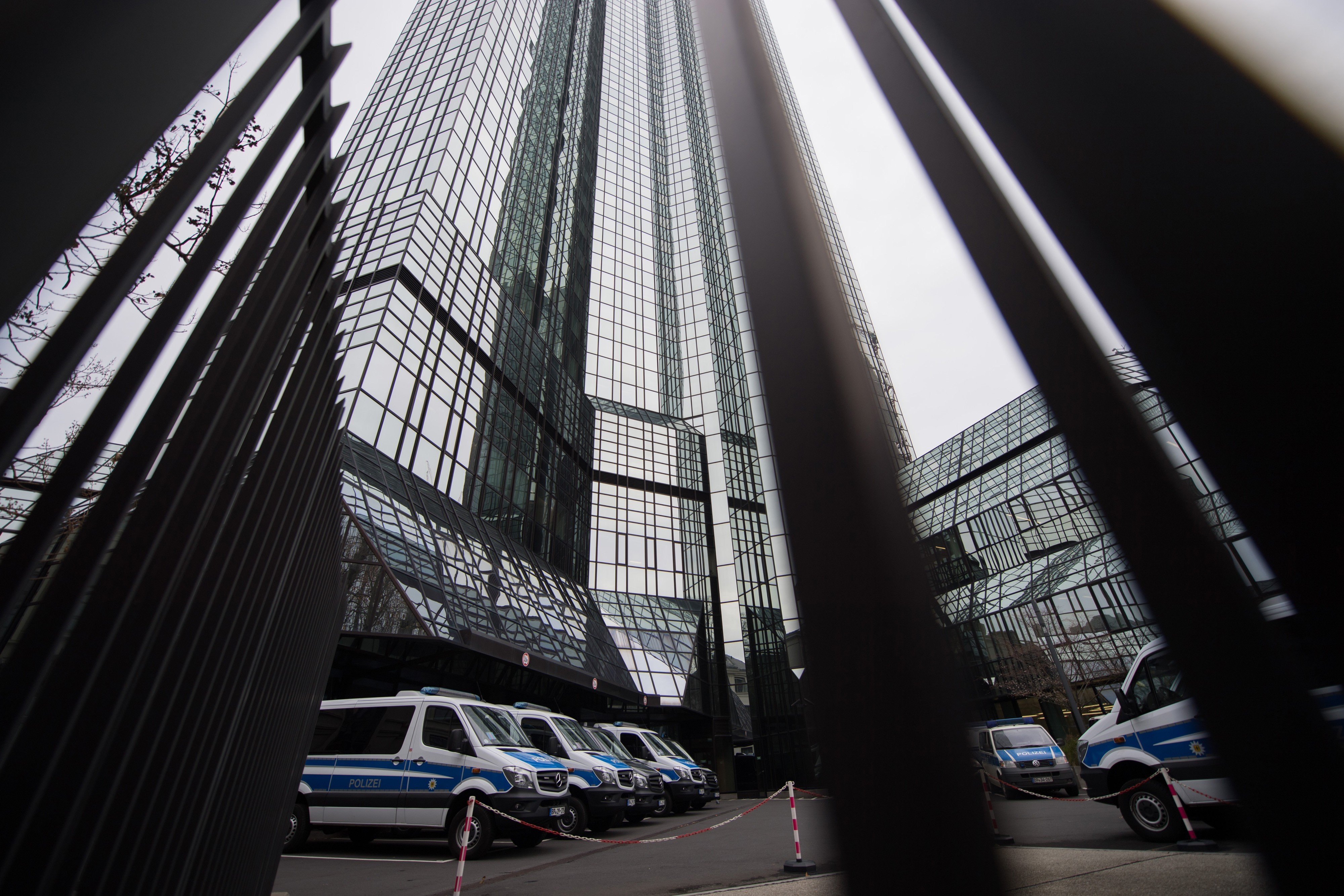 Police vans sit outside the headquarters of Deutsche Bank AG during a police raid. Photo: Bloomberg