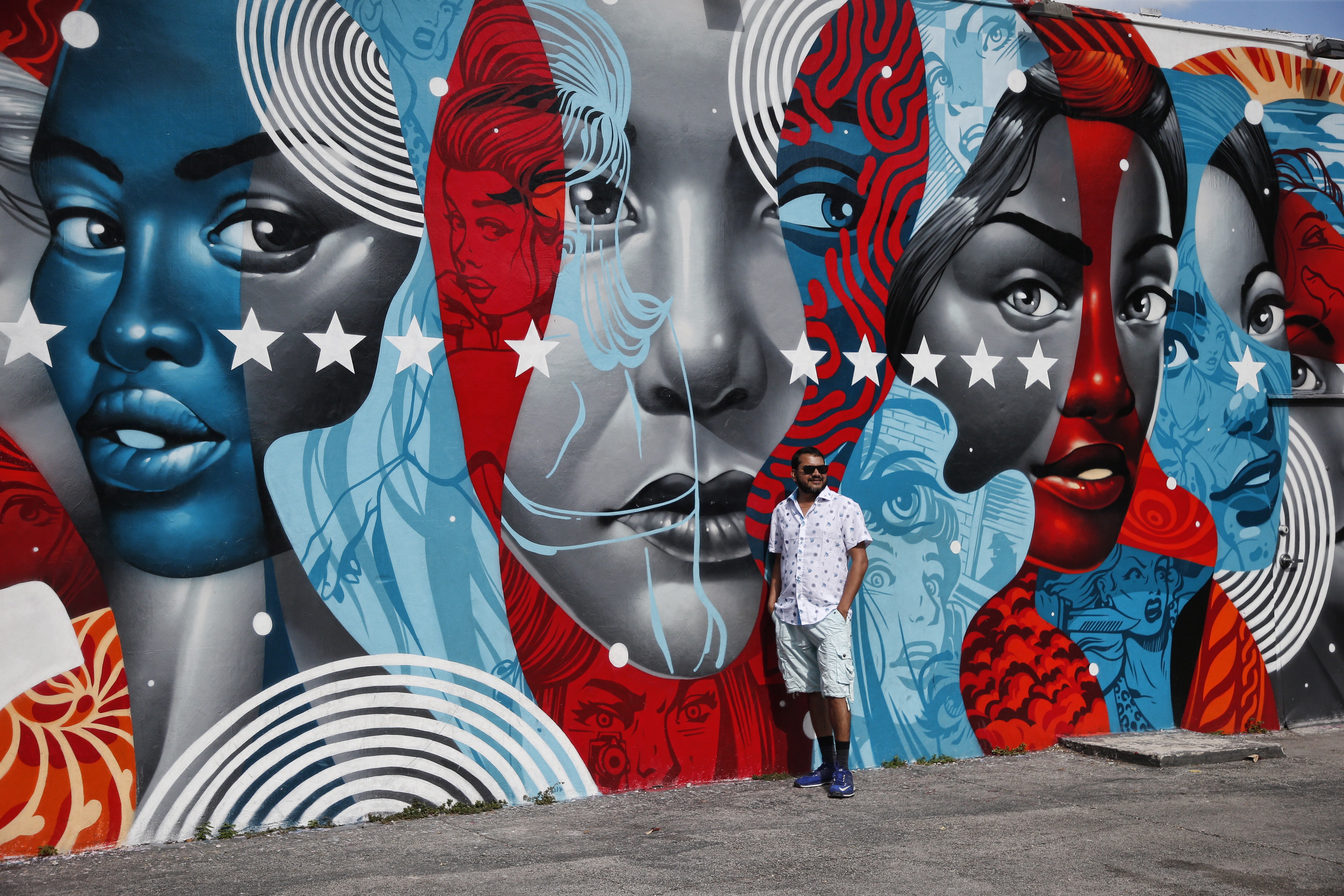 A man poses for a photo in front of a building covered with a mural by US artist Tristan Eaton in the Wynwood district during Art Basel in Miami, Florid. Photo: EPA-EFE