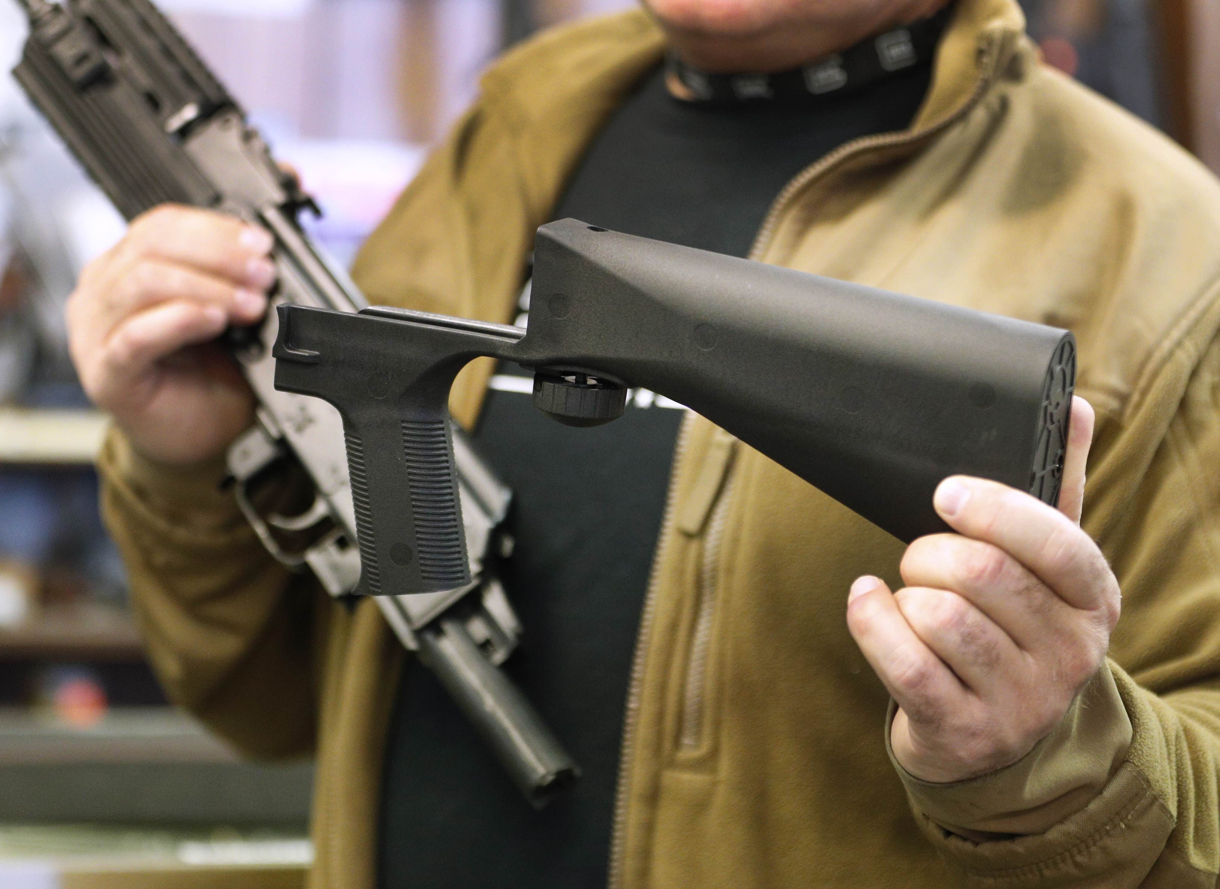 A bump stock device (right), that fits on a semi-automatic rifle to increase the firing speed, making it similar to a fully automatic rifle, is shown next to a AK-47 semi-automatic rifle at a gun store in Salt Lake City, Utah. Photo: Agence France-Presse