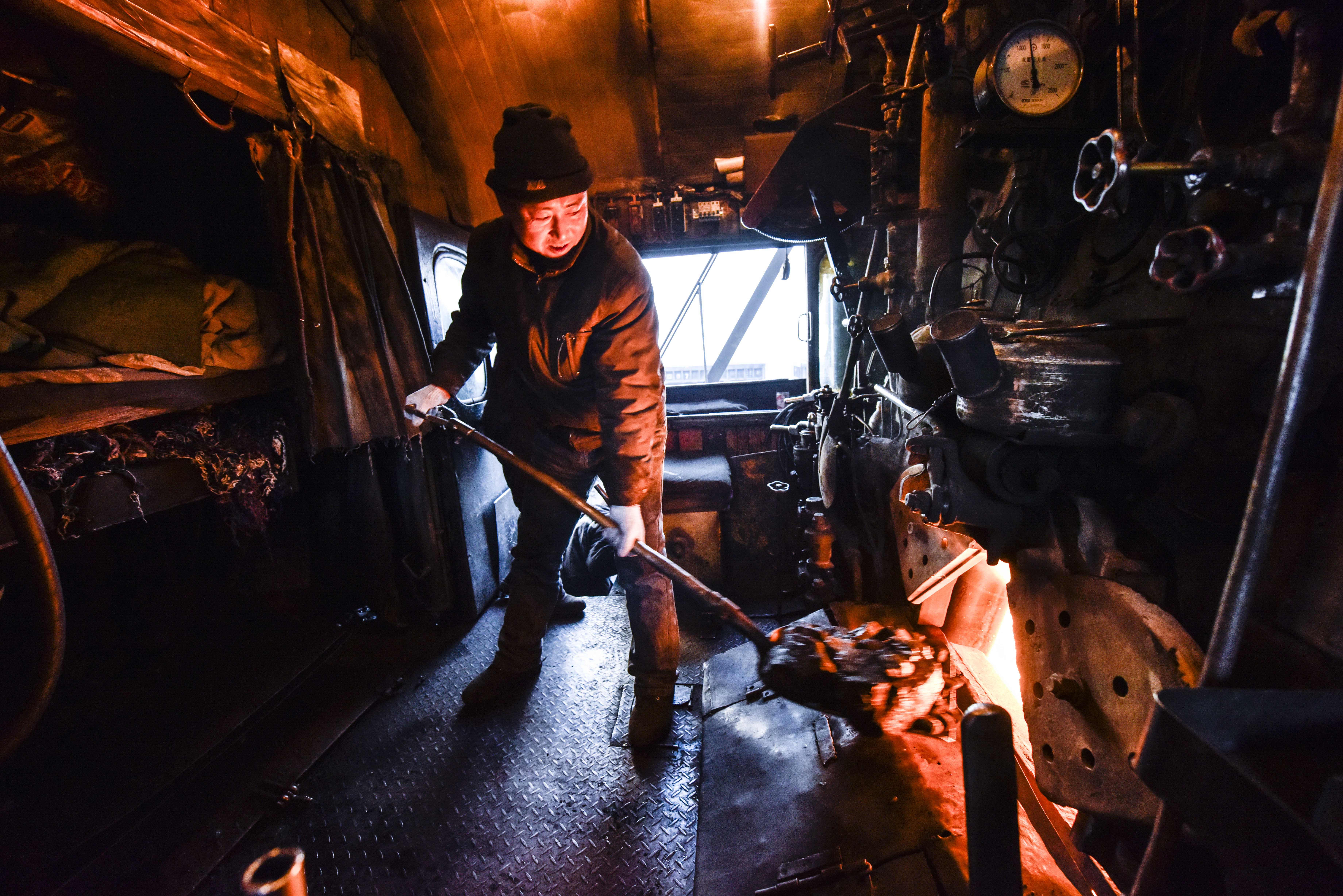 Stoker Dai Yanjia adds coals to a steam locomotive boiler at Sandaoling coal mine area in Hami, in China’s Xinjiang Uygur autonomous region, in January. Photo: Xinhua