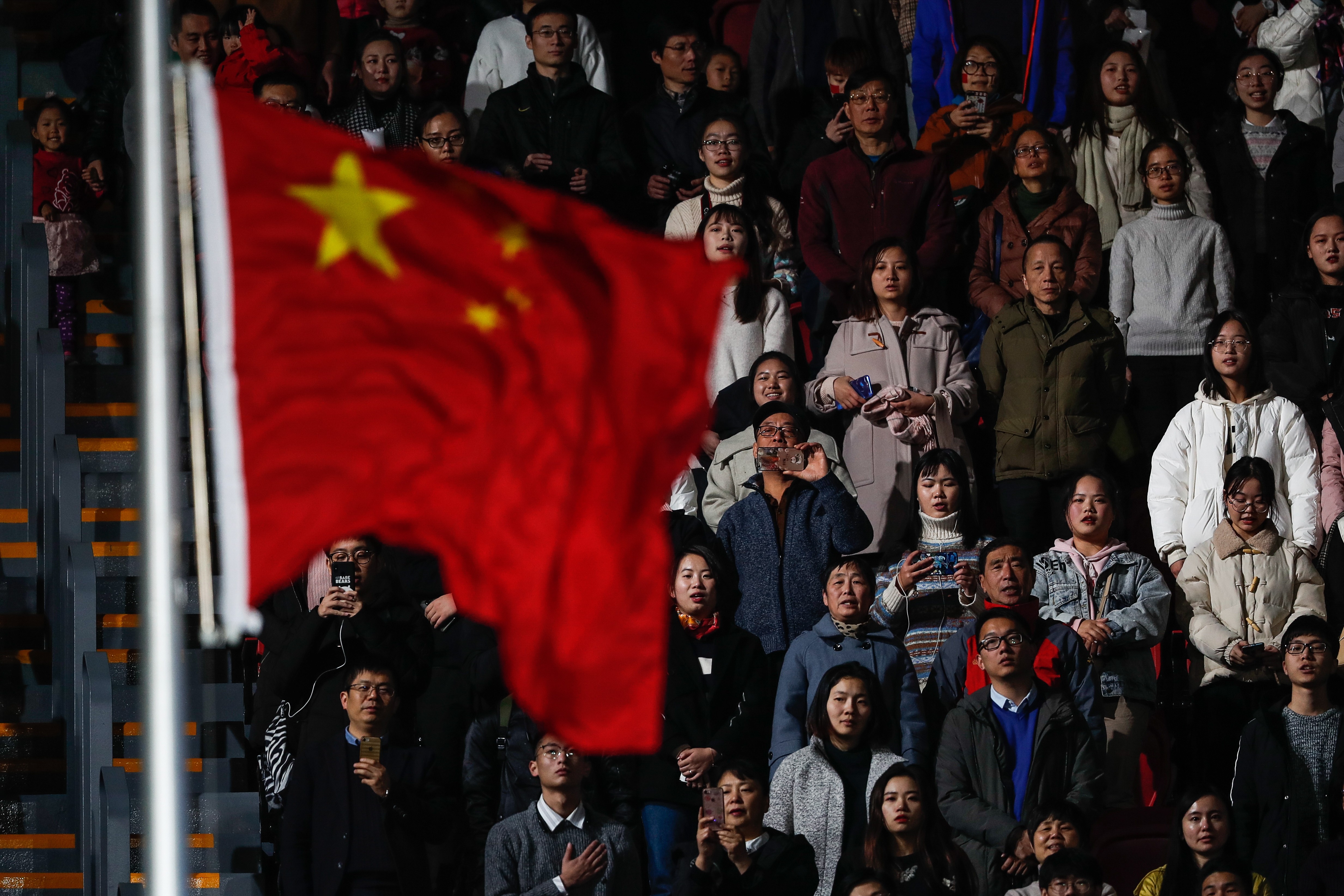 Chinese citizens look at their flag as they sing their national anthem during the opening ceremony of the FINA Swimming Short Course World Championships in Hangzhou on December 11. Photo: EPA-EFE