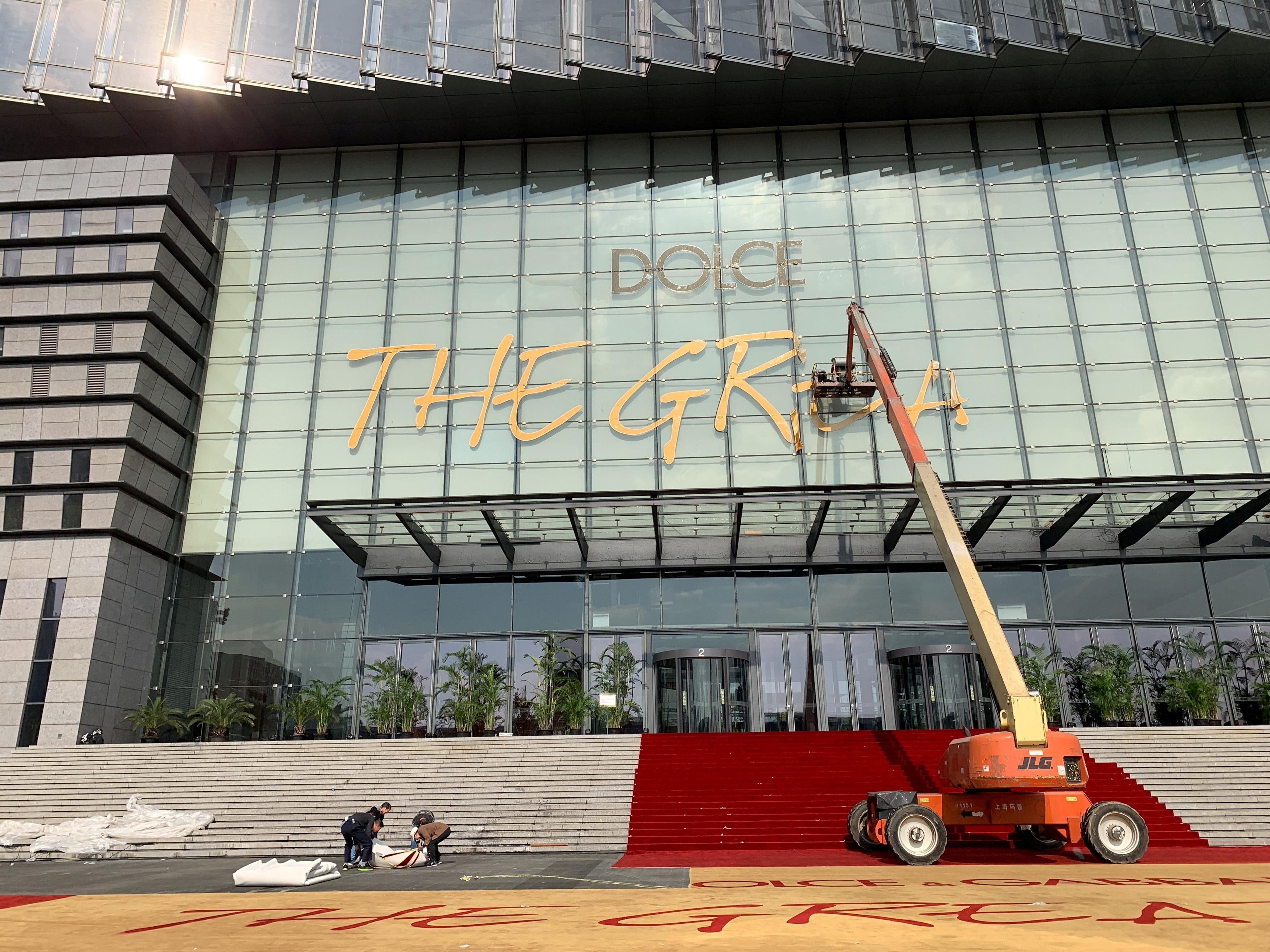 Workers remove the title of Dolce & Gabbana’s fashion show at the Shanghai Expo Centre on November 22, after the show was cancelled in the wake of a Chinese backlash against the fashion brand’s perceived racism. Photo: Reuters