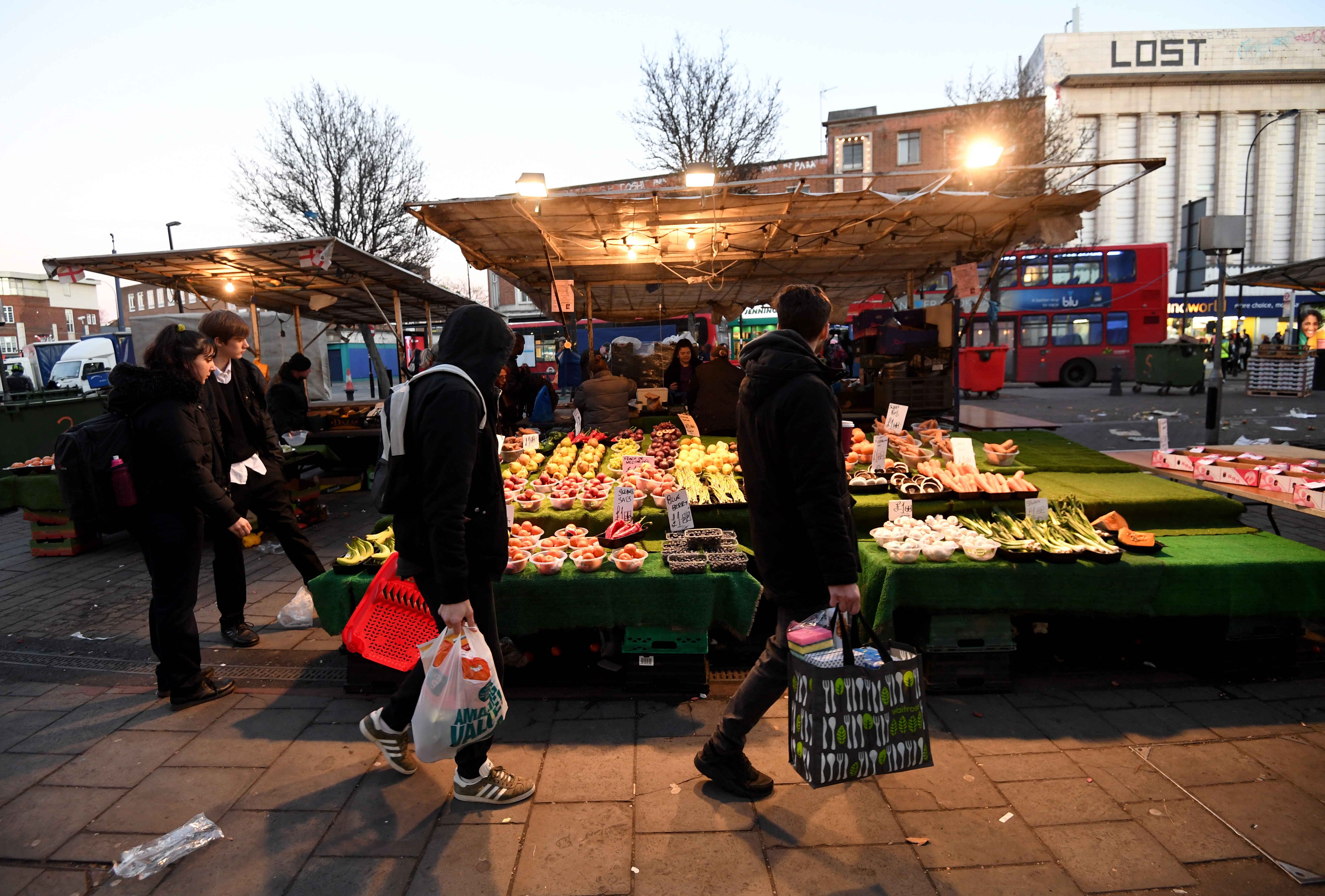 Shoppers walk by a vegetable stand at the Lewisham market in London on Monday. Photo: EPA-EFE