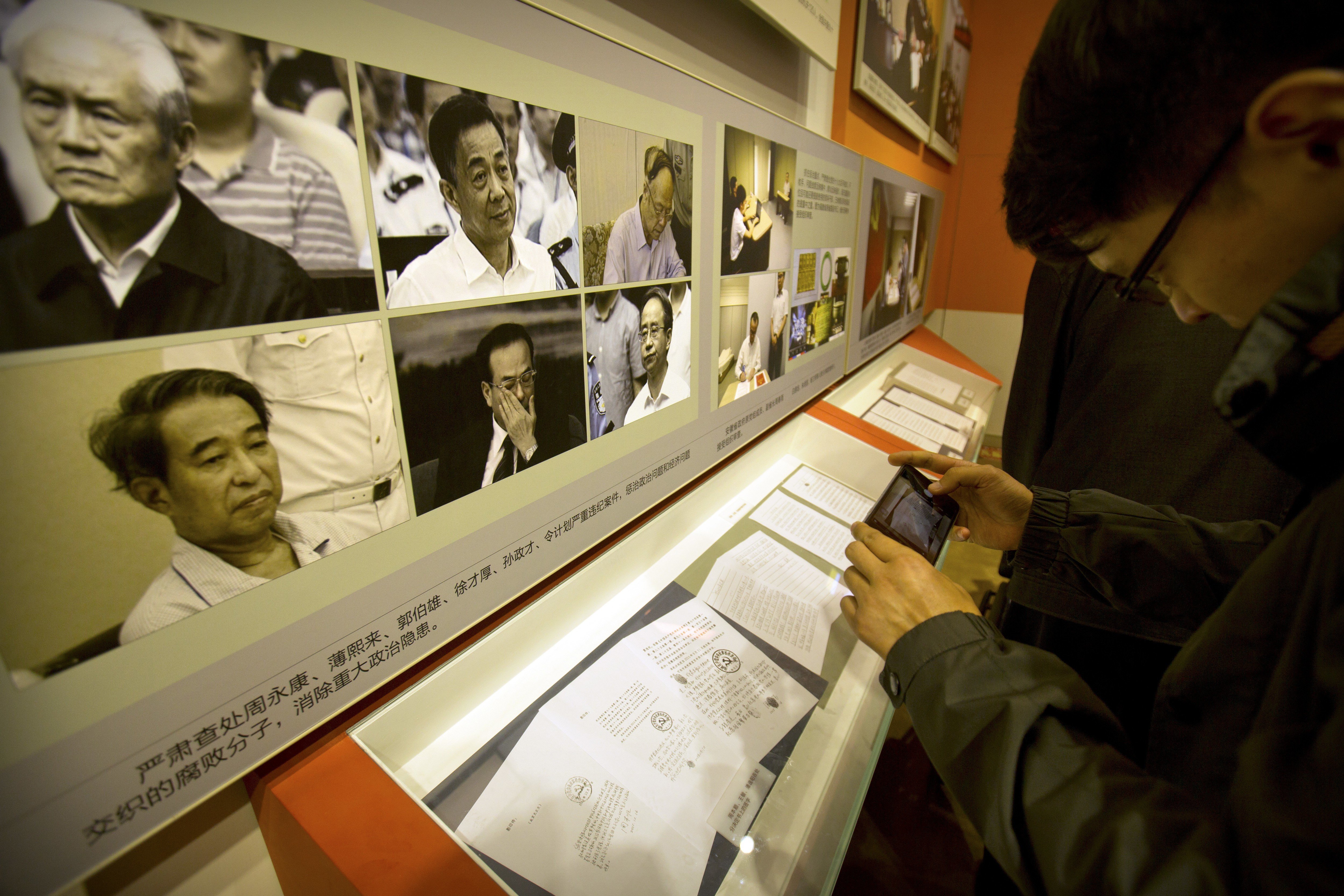A visitor looks at photos of and statements of repentance by corrupt Chinese officials, (clockwise from upper left) Zhou Yongkang, Bo Xilai, Guo Boxiong, Ling Jihua, Sun Zhengcai and Xu Caihou, at an exhibition in Beijing on September 28, 2017. Photo: AP