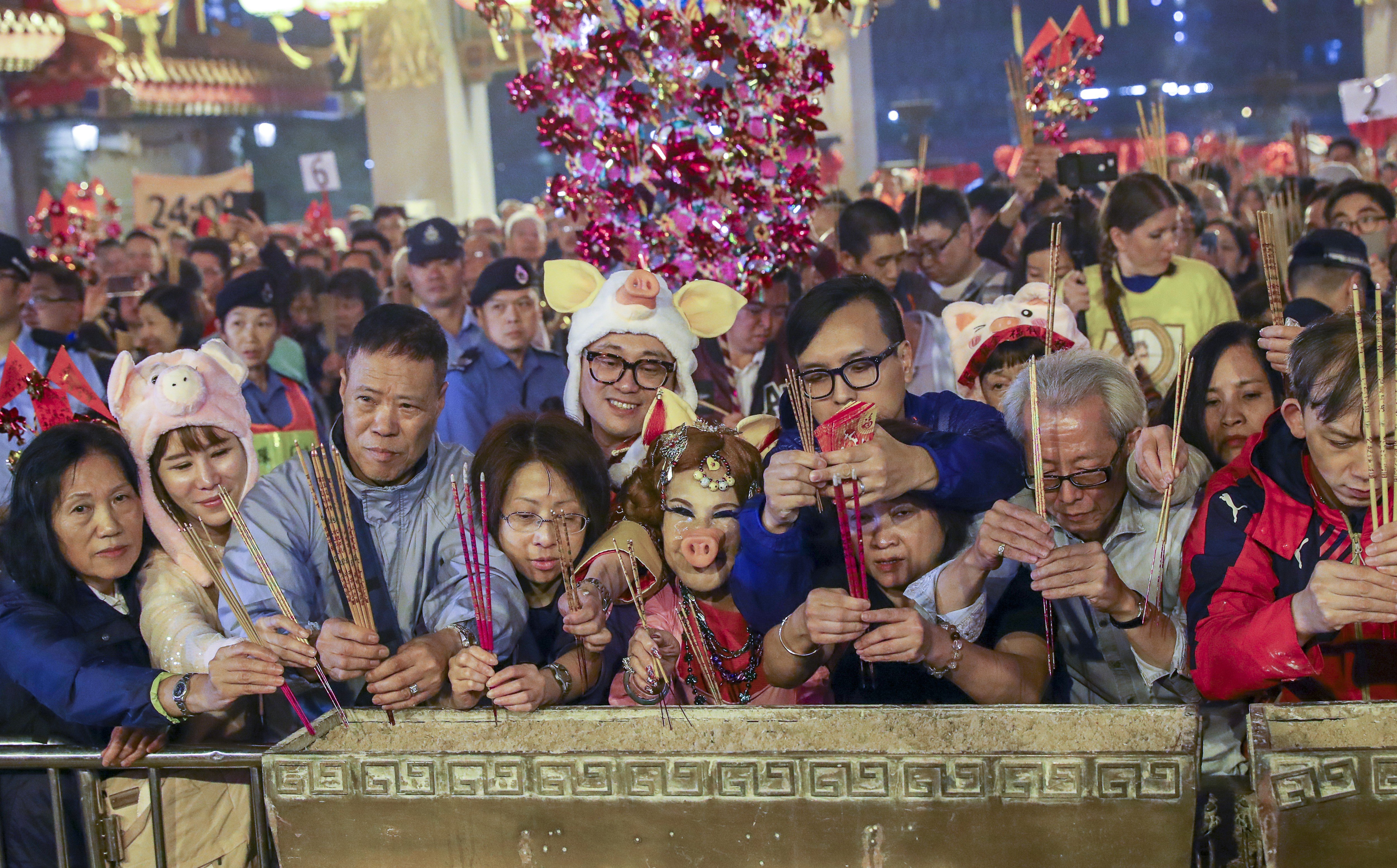 Worshippers, including former actress Lana Wong Hai-wai (centre, in pig costume) offer the first incense at Wong Tai Sin Temple on Lunar New Year's Eve. Photo: Edmond So