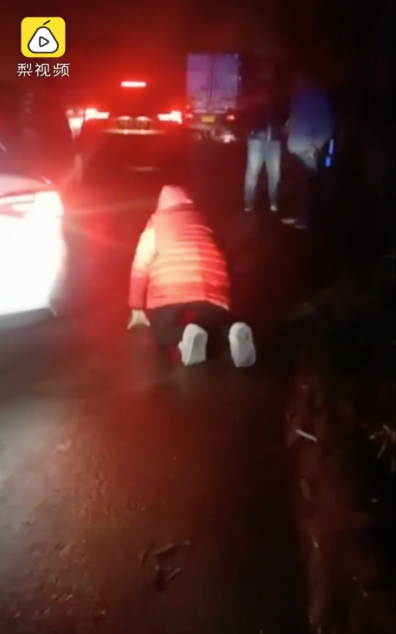 A woman kneels and pleads with motorists to get out of an emergency lane so an ambulance can take her father to hospital in Luan, Anhui province, last week. Photo: Pear Video