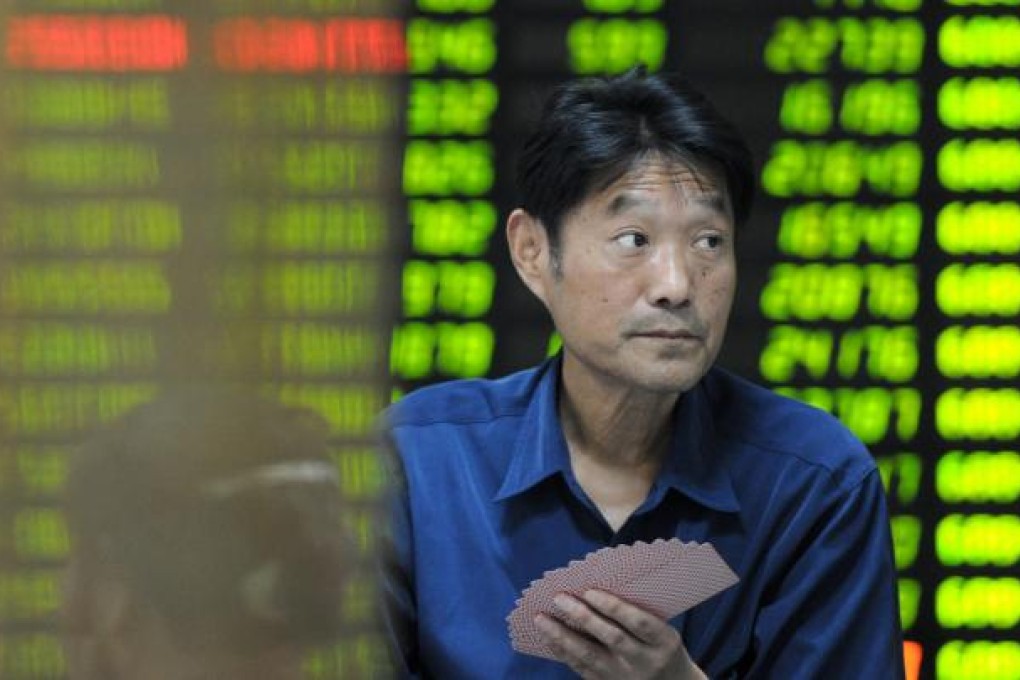 An investor at a brokerage in Nanjing passes the time playing cards - he may soon have more firms from the mainland's west to invest in. Photo: Xinhua