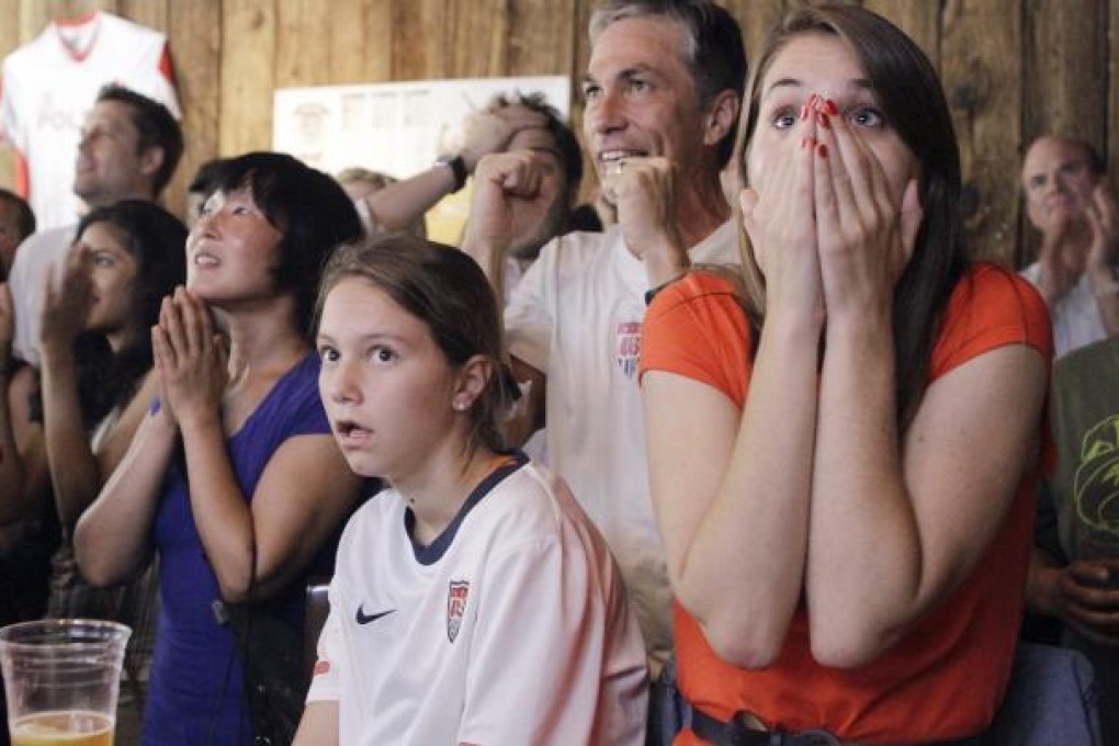 In this Thursday, Aug. 9, 2012 file photo, people react as they watch a television broadcast of the United States women's soccer team taking on Japan in the gold medal match at the 2012 London Summer Olympics, at Nevada Smiths bar in New York. The U.S. won 2-1. The London Olympics may well be remembered as the event that drove home the power of social media, partly to the chagrin but mostly to the benefit of NBC, which controlled images of the games in the United States. Many factors surely drove interest, like compelling competition and the amount of coverage available on TV and online. AP Photo/Alex Katz