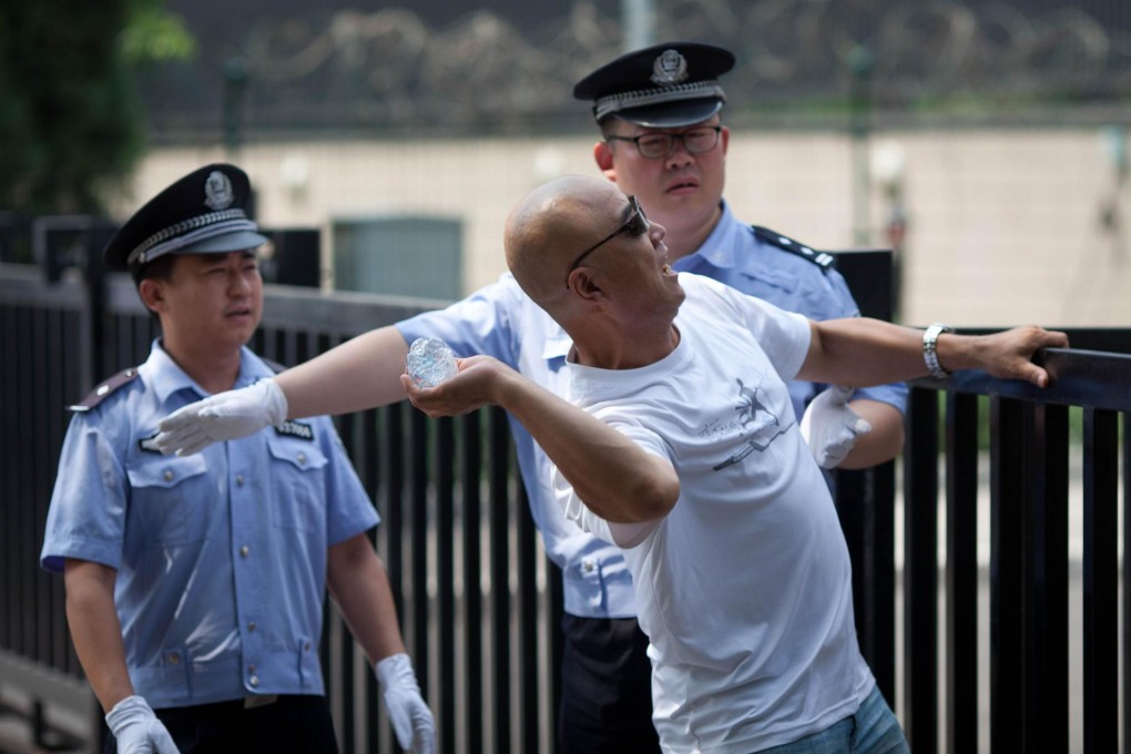 Policemen stand by as a protester throws a bottle outside the Japanese embassy in Beijing in protest at arrests on a disputed island. Photo: AFP