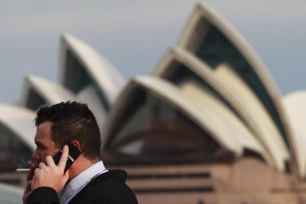 An office worker smokes a cigarette in front of the Sydney Opera House on August 15, 2012. Australia called on the rest of the world to match its tough new anti-tobacco marketing laws after its highest court on Wednesday dismissed a challenge from international cigarette companies in a major test case. REUTERS/Daniel Munoz
