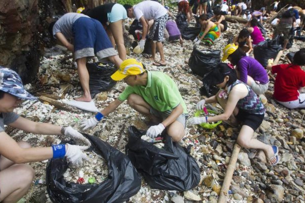 People clean up a beach in Hong Kong, China, 12 August 2012. Over a 150 volunteers from the Hong Kong based NGO, Ecovision moved 217 full bags of plastic, plastic pellets and assorted marine trash off Big Wave Bay beach after Hong Kong suffered it's worst plastic disaster, where 150 tons of plastic pellets where lost at sea during a recent typhoon.  EPA/PAUL HILTON