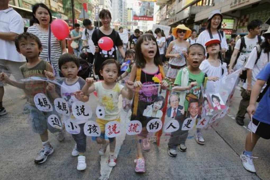 Children chant slogans as they carry a banner featuring portraits of government officials, including Hong Kong's Chief Executive Leung Chun-ying (3rd left), during a protest march against a Chinese patriotic education course in Hong Kong July 29, 2012. REUTERS