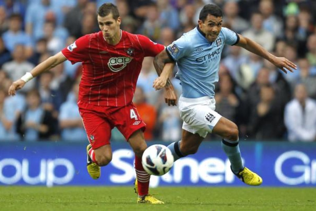 Manchester City's Carlos Tevez battles for the ball with Morgan Schneiderlin of Southampton at the Etihad Stadium. Photo: AFP