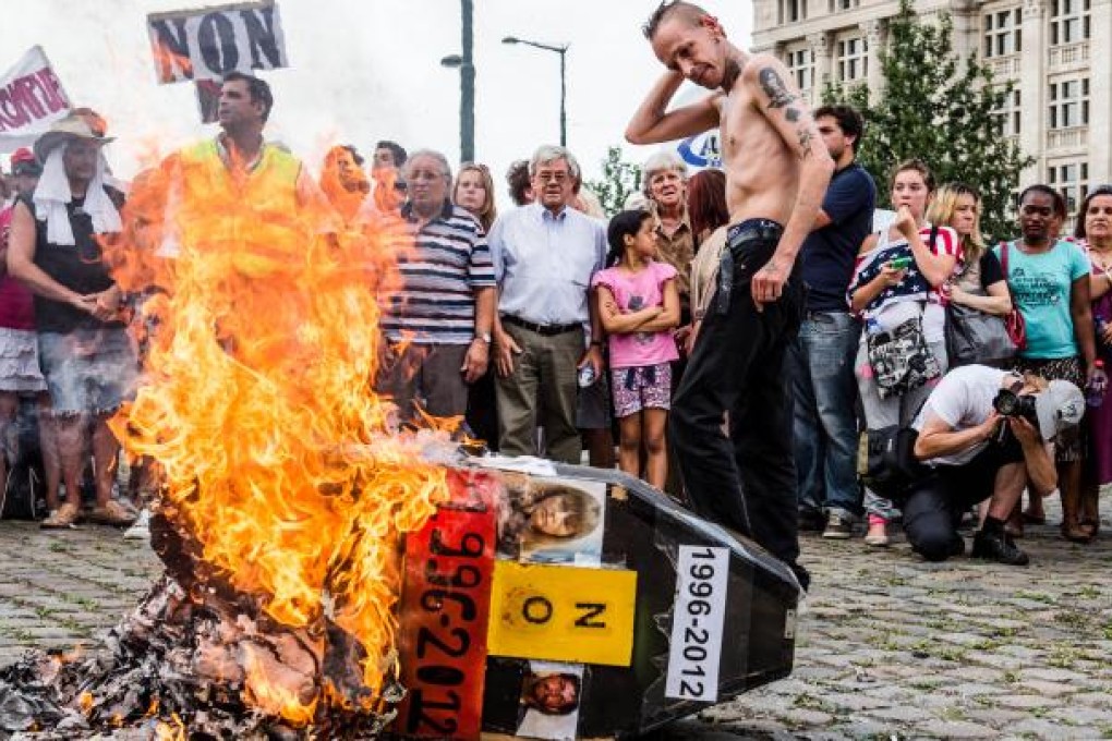 Demonstrators gather around a burning mock coffin with the pictures of  Belgium's child killer Marc Dutroux and his ex-wife Michelle Martin during a march to remember their victims, in Brussels, Sunday Aug. 19, 2012. AP Photo