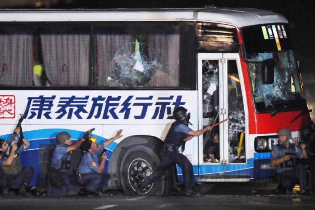 Philippine police try to open the door of the tourist bus carrying Hong Kong tourists which was hijacked in Manila in August 2010 by Rolando Mendoza. Seven tourists and their tour guide were killed. Photo: AFP