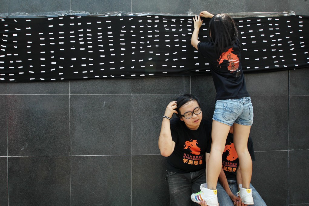At the government headquarters yesterday, pupils erect a banner with signatures of people opposed to national education. Photo: Dickson Lee