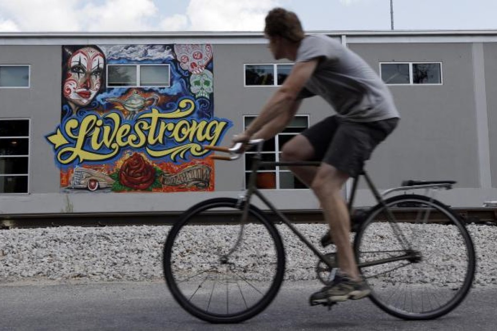 A cyclist passes a mural on the building housing the Lance Armstrong foundation, Livestrong, on Friday in Austin, Texas. Photo: AP