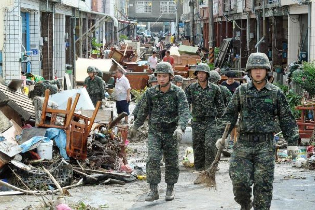 Soldiers help residents in southern Taiwan clean up debris left in areas affected by floods brought on by Typhoon Tembin. Photo: AFP