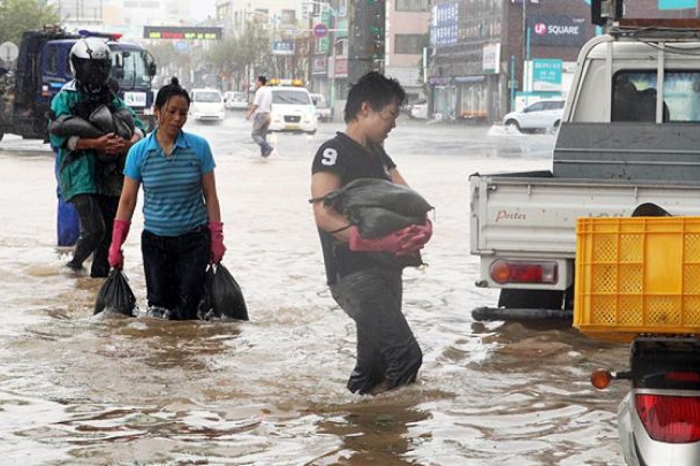 Residents of Mokpo, South Korean, rush to build barriers to stave off flood waters a Typhoon Tembin makes landfall 300km south of Seoul on Thursday. Photo: AFP