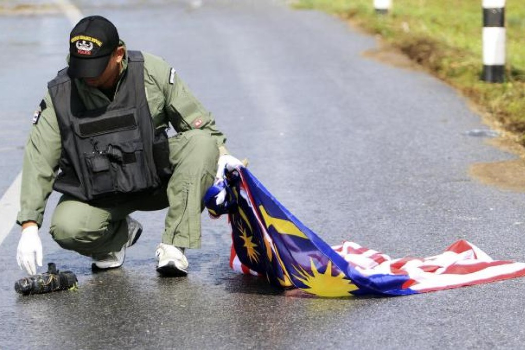 A Thai officer tries to inspect a suspected bomb. Photo: Reuters