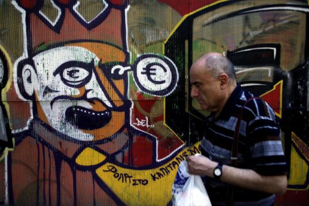 A pedestrian walks past anti-euro-zone graffiti in Athens. But there is more optimism on European company debt. Photo: Bloomberg