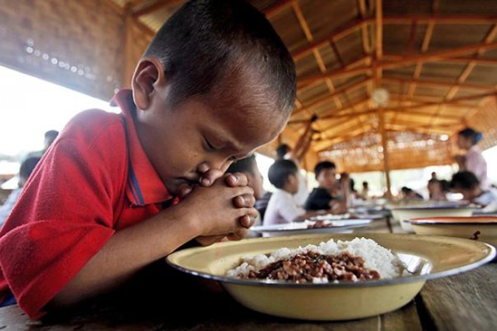 A Kachin refugee boy prays before a meal at a UN refugee camp in northern Myanmar. Photo: EPA