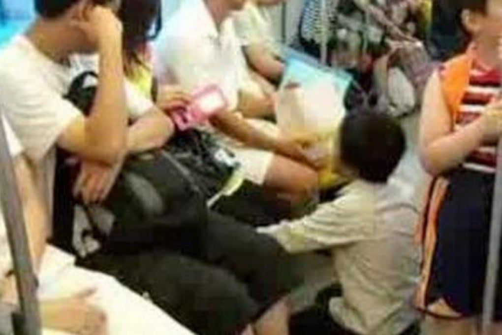 A panhandler kneels in front of the commuters on a Shanghai subway train. Photo: SCMP