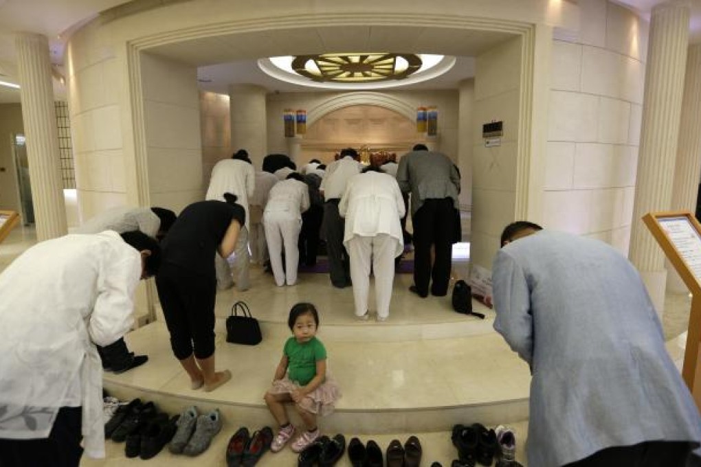 A girl sits on the steps of a Unification church in Seoul yesterday as followers pray at a service to honour their leader Sun Myung Moon, who has died at the age of 92. Photo: AP