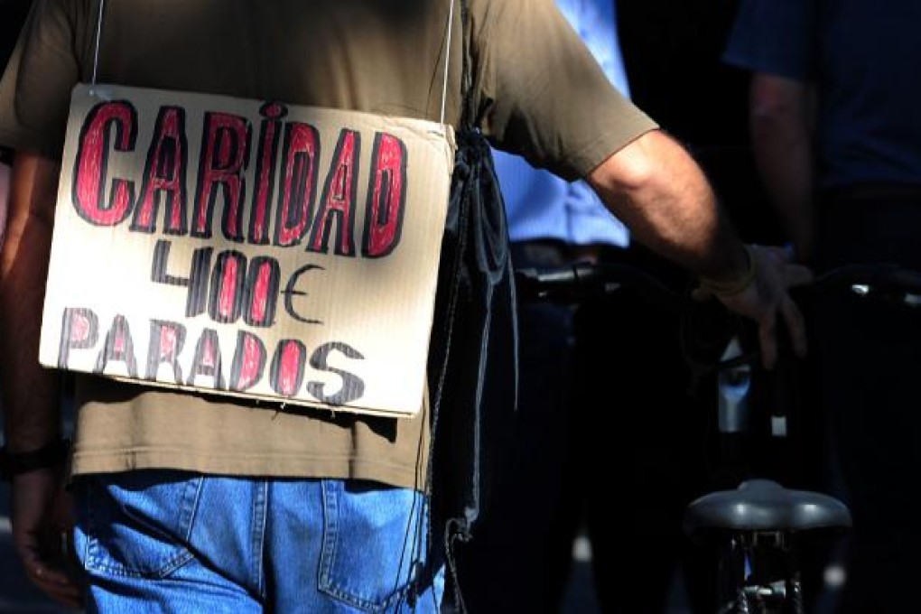 A man holds a placard reading "Charity 400€ unemployed" , referring to Madrid's decision to extend the life of a 400-euro (US$500) monthly payment for jobless people whose unemployment benefits come to an end. Photo: AFP