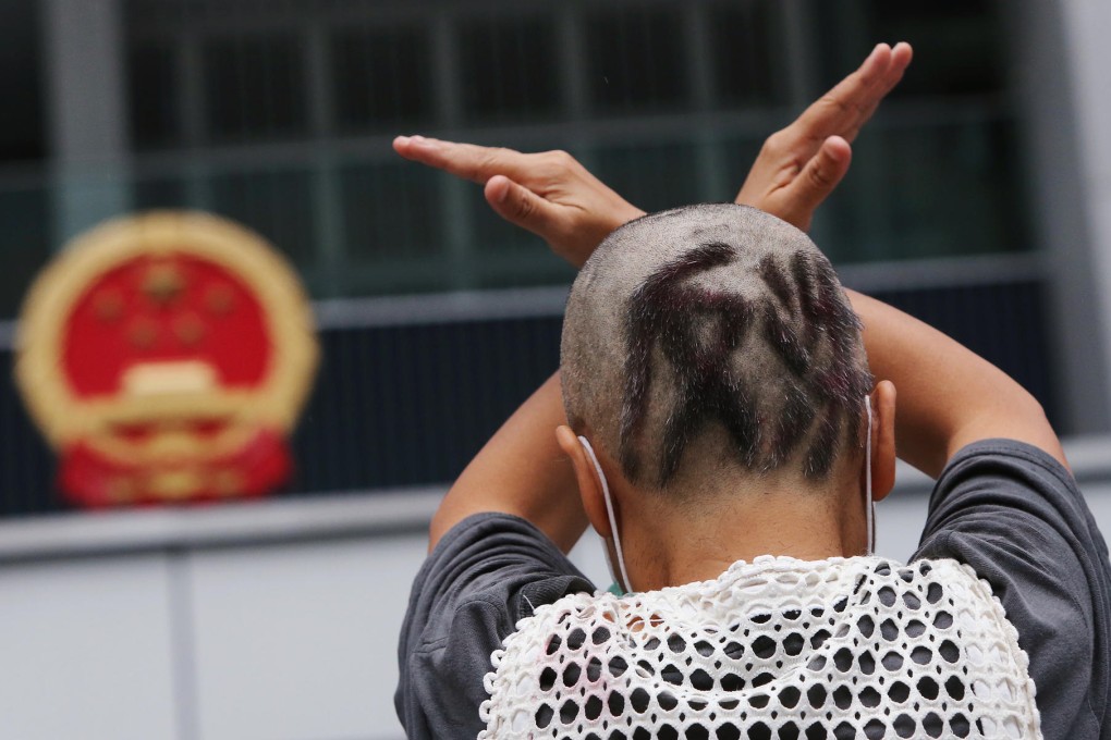 A woman who has had her hair shaved to read "resistance" joins the protest outside the government headquarters at Tamar. Photo: David Wong