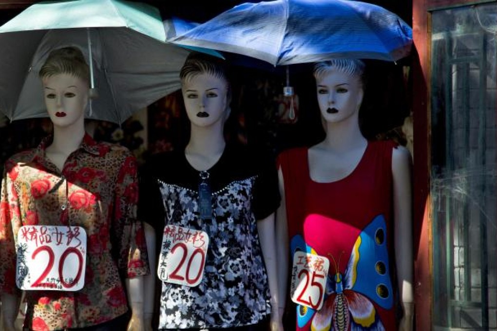 Mannequins displaying fashion dresses for sale get shade from umbrellas at a shop along a Hutong alley in Beijing Monday, Sept. 3, 2012. China's manufacturing decelerated further in August while construction and services grew at a slow rate, according to two surveys Monday, adding to conflicting signals about whether the country's slowdown is bottoming out. AP Photo/Andy Wong