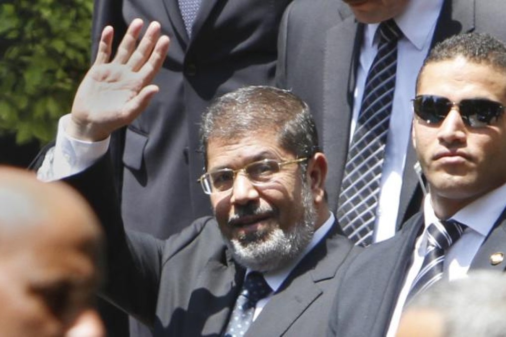 Egyptian President Mohammed Mursi waves to photographers as he leaves the Arab League headquarters in Cairo. Photo: AP