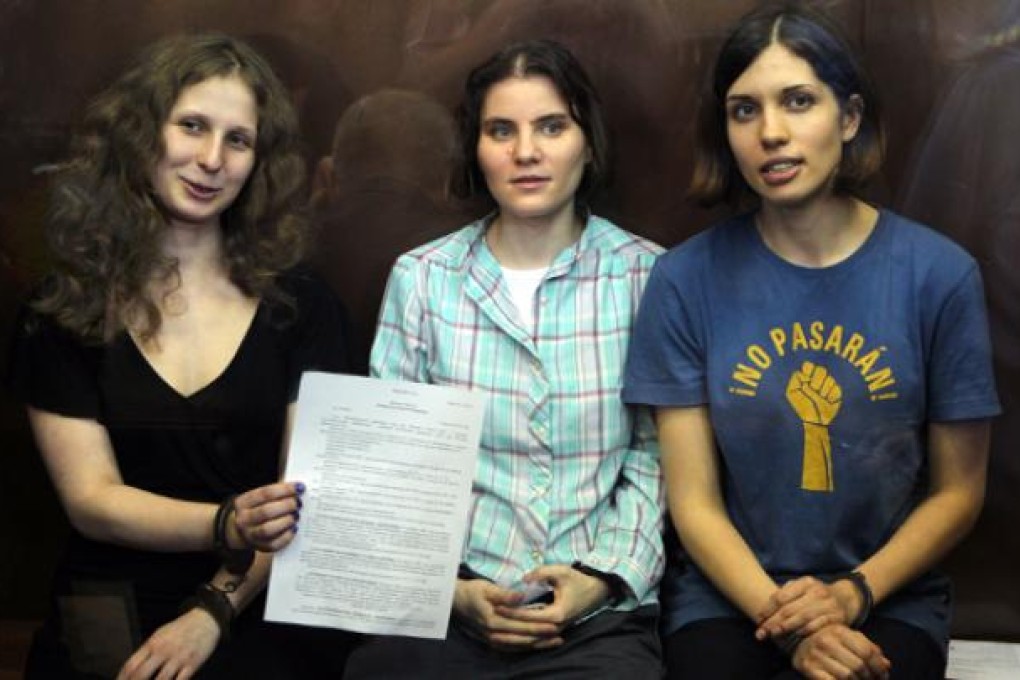 Pussy Riot members, from left, Maria Alekhina, Yekaterina Samutsevich, and Nadezhda Tolokonnikova show the court's verdict as they sit in a glass cage at a courtroom in Moscow. Photo: AP