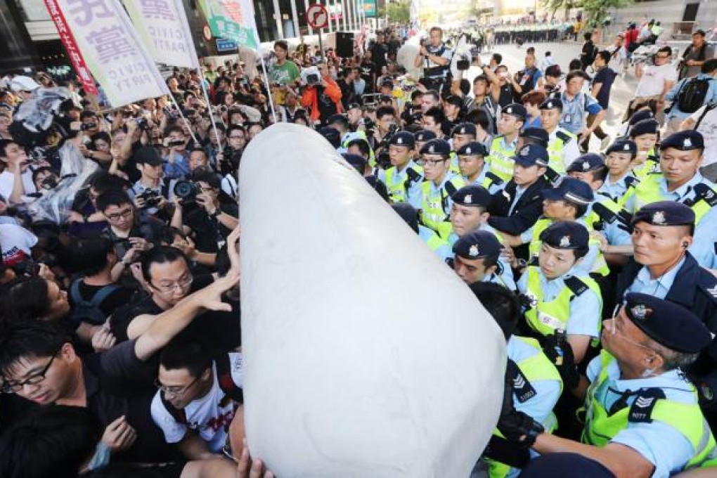 Protesters attempt to push past a water-filled crowd-control barrier closing off a designated protest zone outside Central Plaza in Wan Chai. Photo: Sam Tsang
