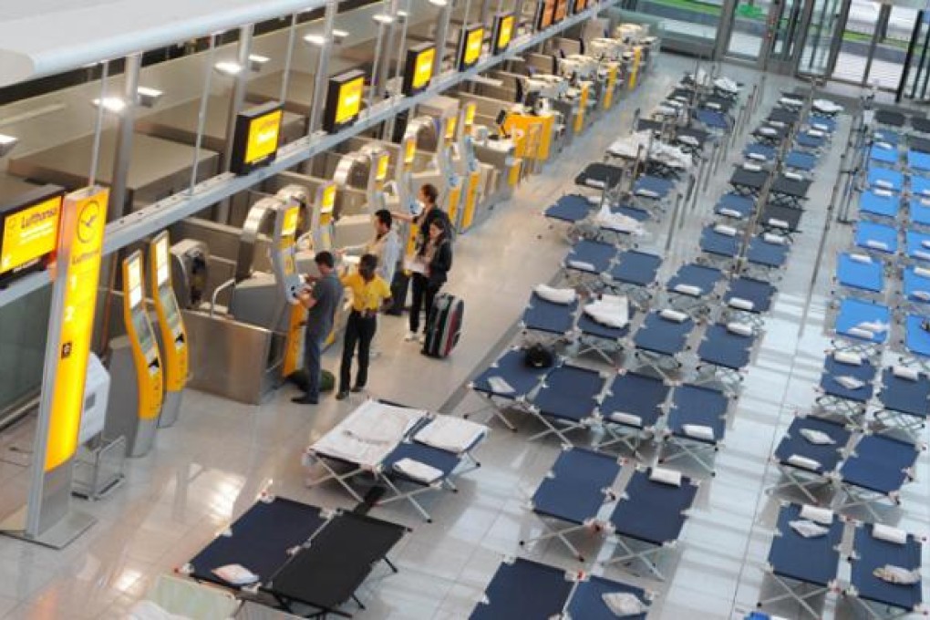 Flight passengers stand at the Lufthansa check-in in front of camp beds at the Franz-Josef-Strauss airport in Munich, on Wednesday. Photo: AFP