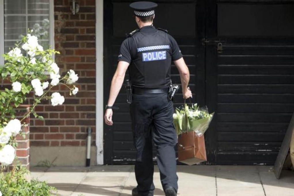 A policeman delivers flowers to the home of Saad al-Hilli in Claygate, Surrey. French police say they have no motive for the brutal killings. Photo: Reuters