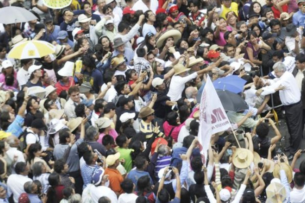 Mexican leftist leader Andres Manuel Lopez Obrador, right, greets his supporters during a rally at Zocalo Square in Mexico City on Sunday. Photo: EPA