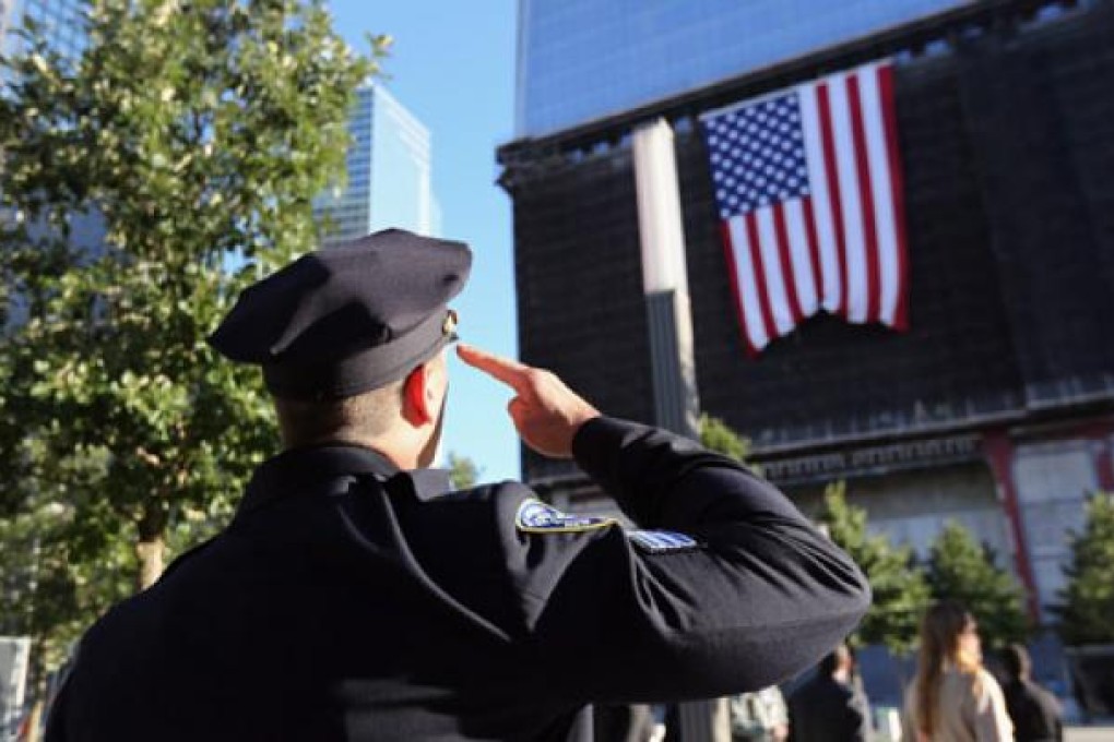 A New York police officer salutes the American flag hanging from One World Trade Centre in Manhattan. Photo: EPA