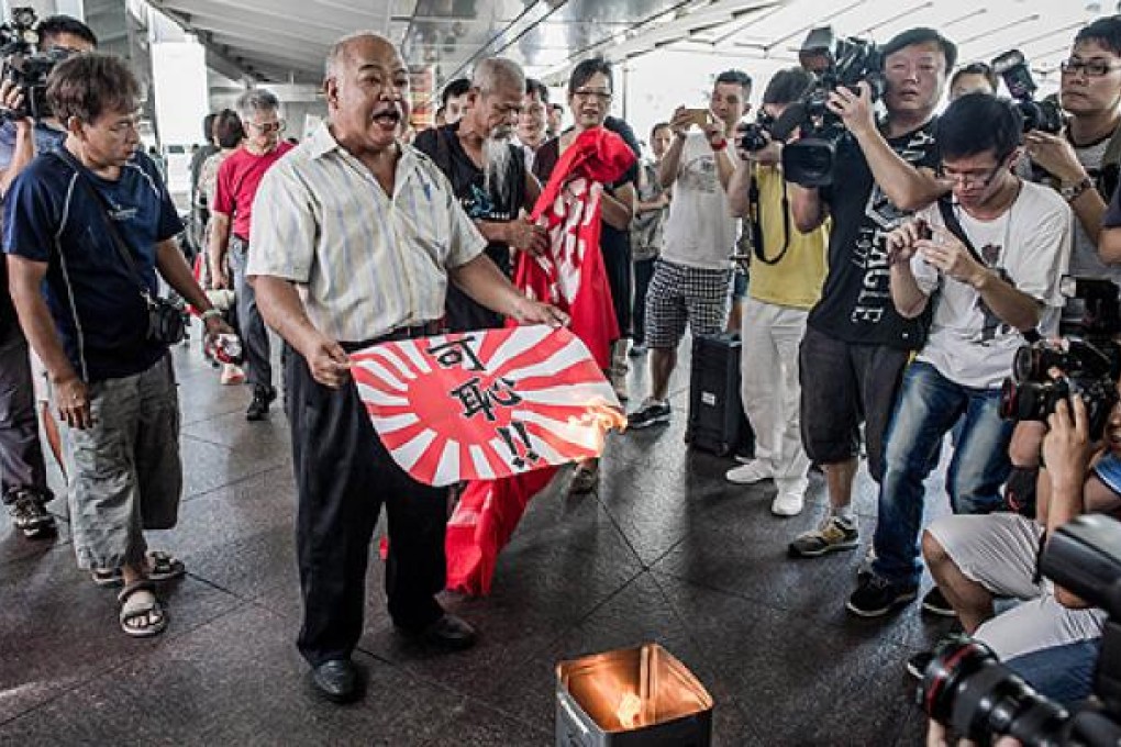 Activist Tsang Kin-shing burns a paper Japanese imperial military flag outside the consulate in Central, Hong Kong, on Wednesday. Photo: AFP