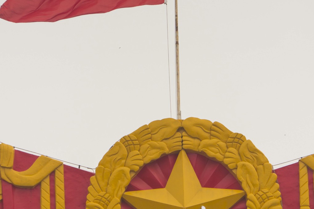 A worker cleans the Chinese national crest overlooking Tiananmen Square in Beijing on September 11,  2012. Photo: EPA