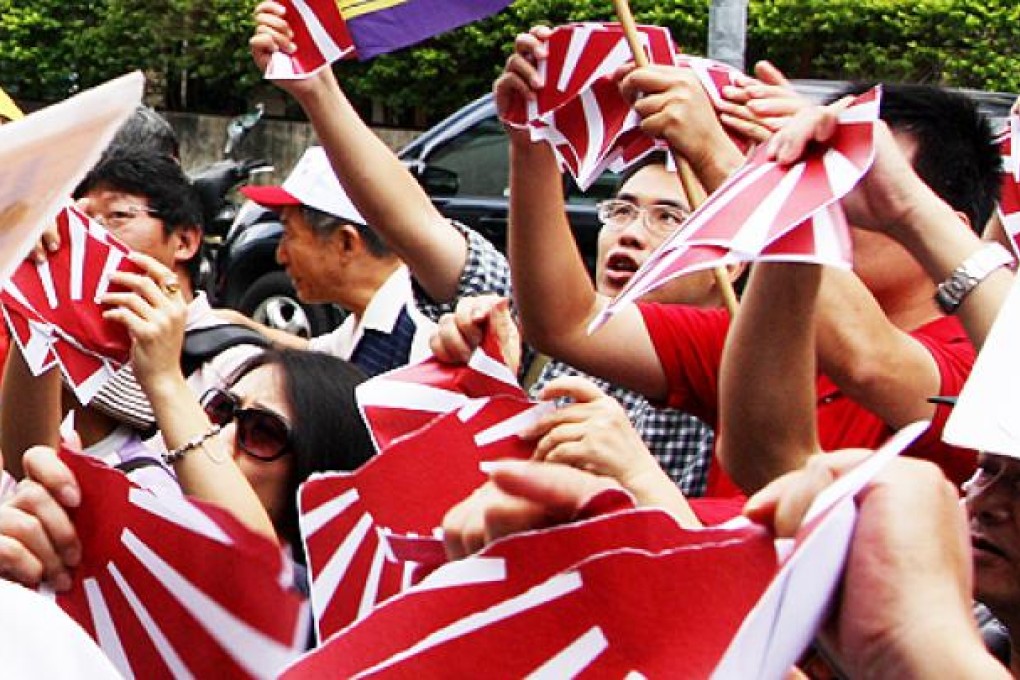 Taiwanese activists rip up papers of the Japanese imperial flag outside the Japanese consulate in Taipei on Wednesday. Photo: AFP