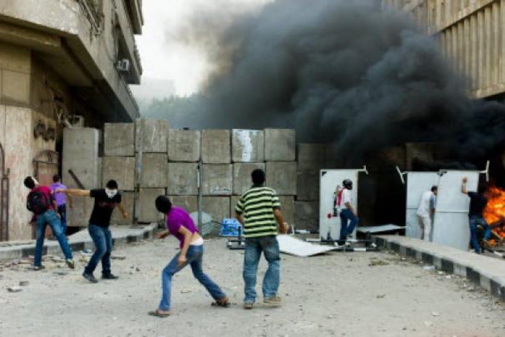 Protesters throw stones over a wall set outside the US embassy in Cairo in Egypt. Photo: Xinhua