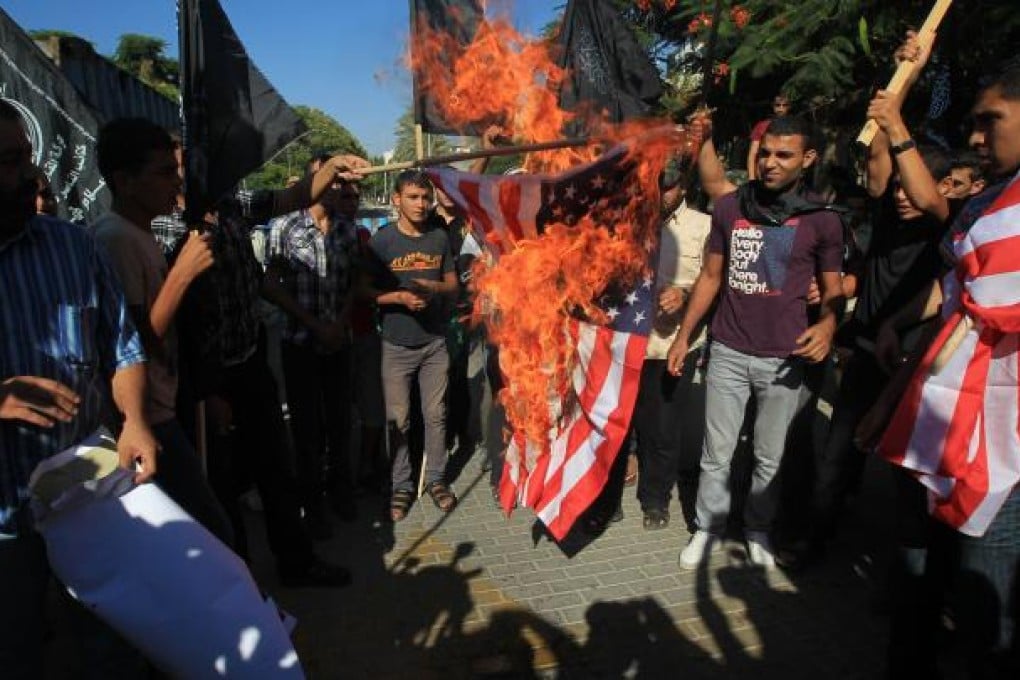 Palestinian men burn the US flag during a demonstration against a film deemed offensive to Islam, on September 12, 2012 in front of the United Nations headquarters in Gaza City. Photo: AFP