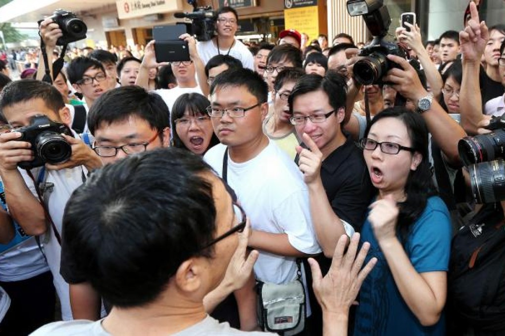 A supporter of the cross-border traders tries to placate angry local protesters outside Sheung Shui station yesterday. Photo: David Wong