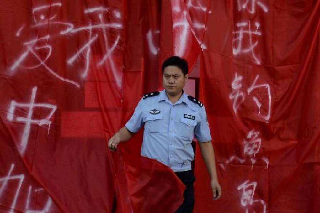 A policeman emerges from a closed Japanese restaurant covered with flags and banners saying "it is Chinese-owned". Photo: AFP