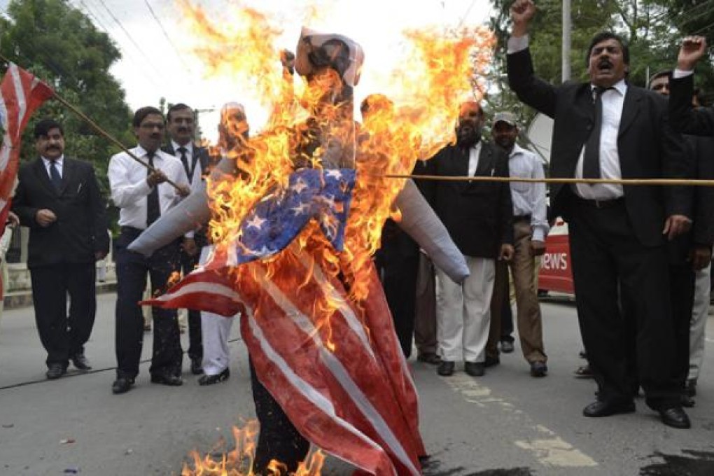 Pakistani lawyers shout slogans as they burn a US flag and an effigy of US President Barack Obama and Florida pastor Terry Jones during a protest in Multan on Monday. Photo: AFP